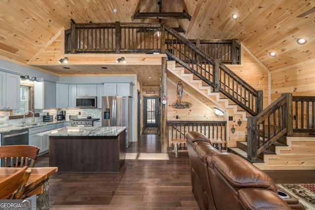 kitchen featuring light stone counters, dark hardwood / wood-style floors, wooden walls, wood ceiling, and appliances with stainless steel finishes