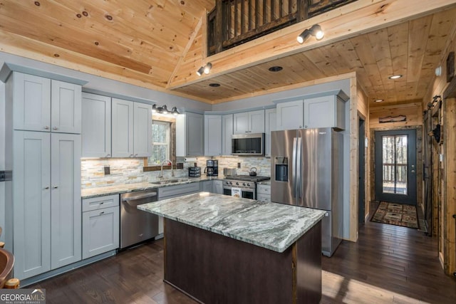 kitchen with light stone countertops, appliances with stainless steel finishes, sink, a center island, and dark hardwood / wood-style floors