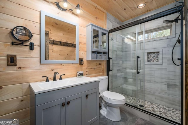 bathroom featuring vanity, toilet, a shower with shower door, and wood walls