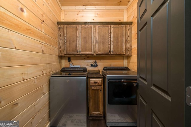 laundry room featuring washing machine and clothes dryer, dark hardwood / wood-style floors, cabinets, and wood walls