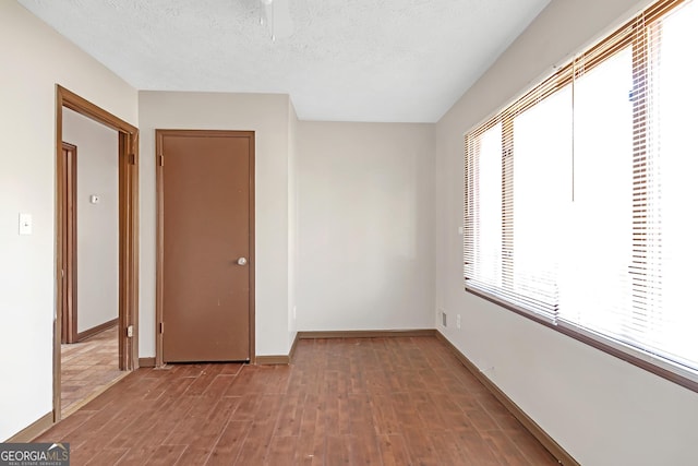 unfurnished bedroom with multiple windows, a textured ceiling, and hardwood / wood-style flooring