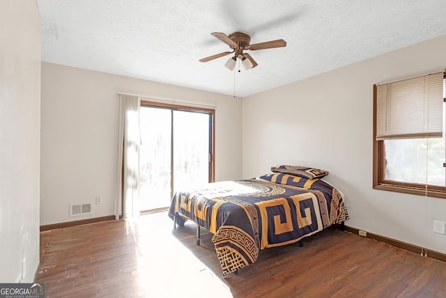 bedroom featuring access to exterior, ceiling fan, dark wood-type flooring, and a textured ceiling