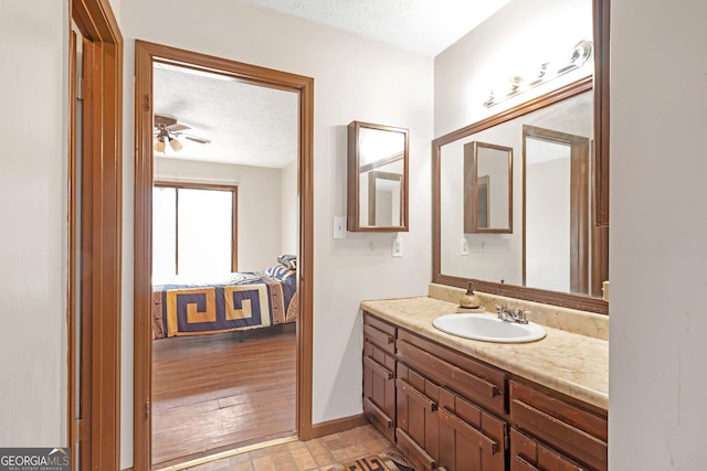 bathroom featuring hardwood / wood-style floors, vanity, ceiling fan, and a textured ceiling