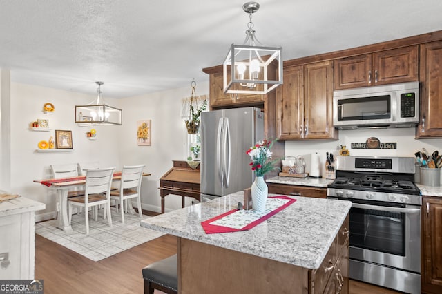 131 Logan Cir, Ellijay, GA 30540 - kitchen featuring appliances with stainless steel finishes, a chandelier, wood finished floors, light stone countertops, and a center island