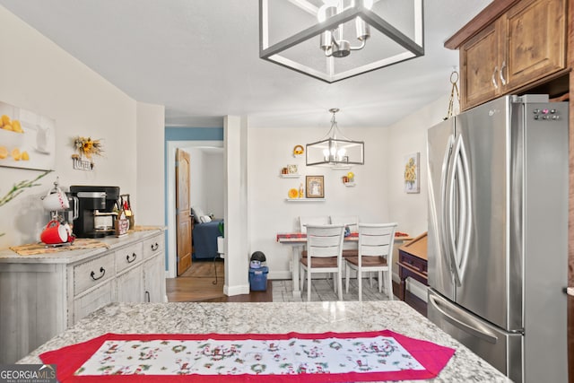 kitchen with a chandelier, hardwood / wood-style flooring, stainless steel refrigerator, and hanging light fixtures