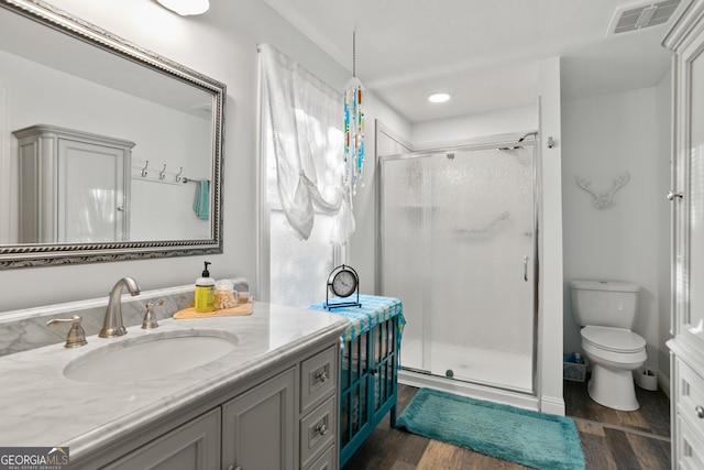 bathroom featuring vanity, wood-type flooring, a shower with shower door, and toilet