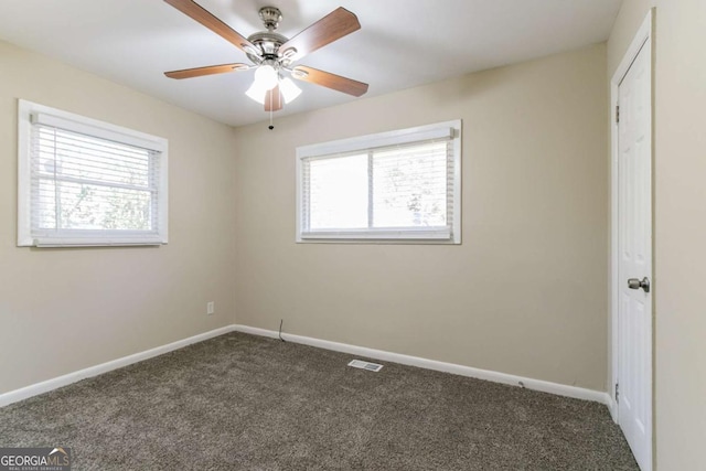 spare room with ceiling fan and dark colored carpet