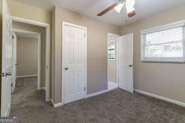 unfurnished bedroom with ceiling fan, a closet, and dark colored carpet