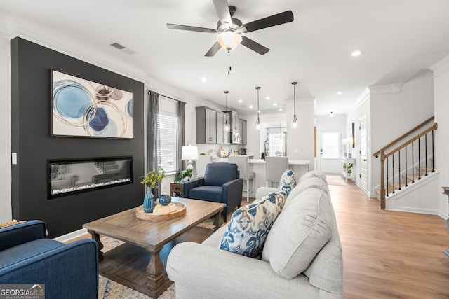 living room with light hardwood / wood-style flooring, ceiling fan, a healthy amount of sunlight, and crown molding