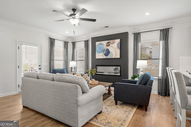 living room featuring crown molding, ceiling fan, a healthy amount of sunlight, and light wood-type flooring