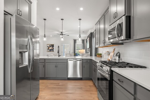 kitchen featuring gray cabinetry, sink, ceiling fan, light wood-type flooring, and appliances with stainless steel finishes