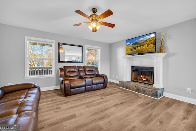 living room with light wood-type flooring, plenty of natural light, and a stone fireplace