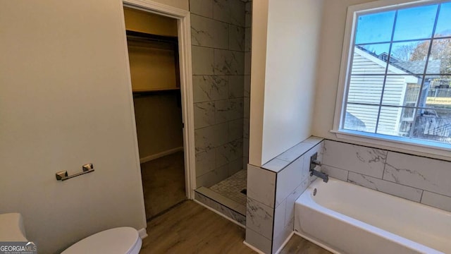 bathroom featuring toilet, plus walk in shower, and hardwood / wood-style flooring