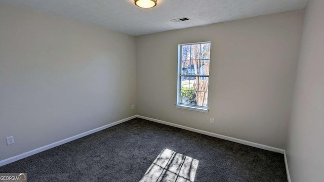 empty room featuring dark carpet and a textured ceiling