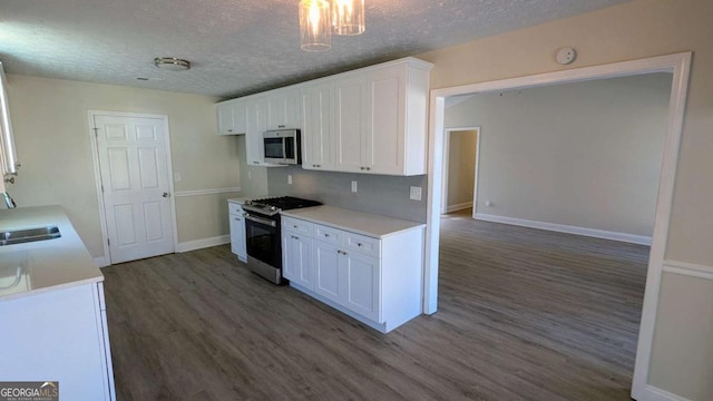 kitchen featuring dark hardwood / wood-style flooring, white cabinets, stainless steel appliances, and a textured ceiling