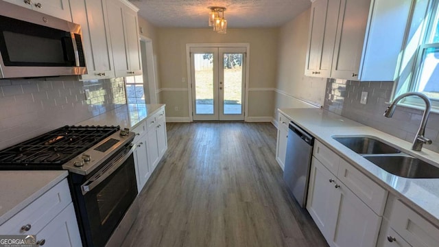 kitchen featuring french doors, sink, a textured ceiling, white cabinets, and appliances with stainless steel finishes