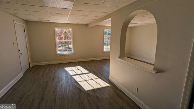 spare room featuring dark hardwood / wood-style flooring and a paneled ceiling