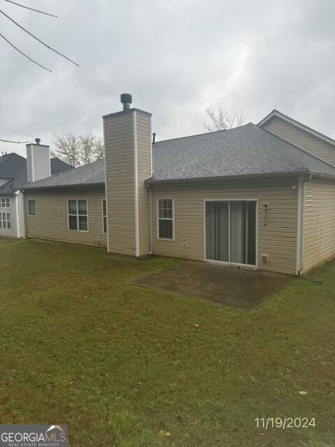 rear view of property featuring a yard and a patio area