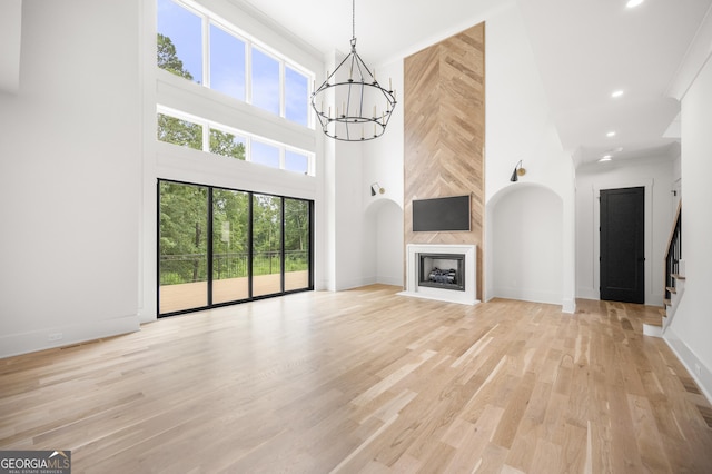 unfurnished living room with a wealth of natural light, light hardwood / wood-style floors, and a high ceiling