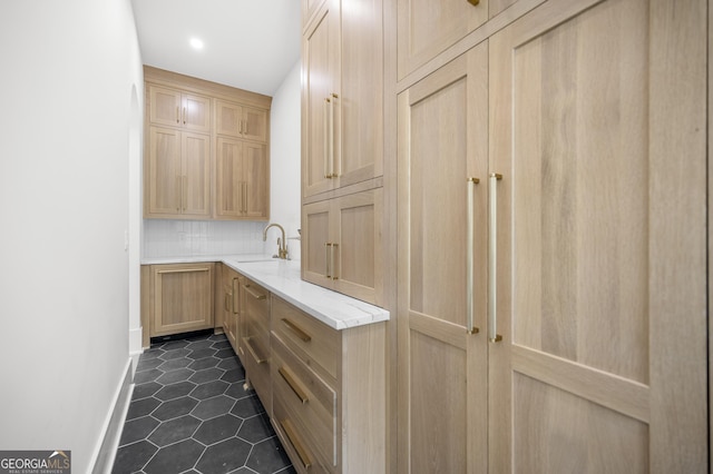 interior space with light brown cabinets, dark tile patterned flooring, and sink