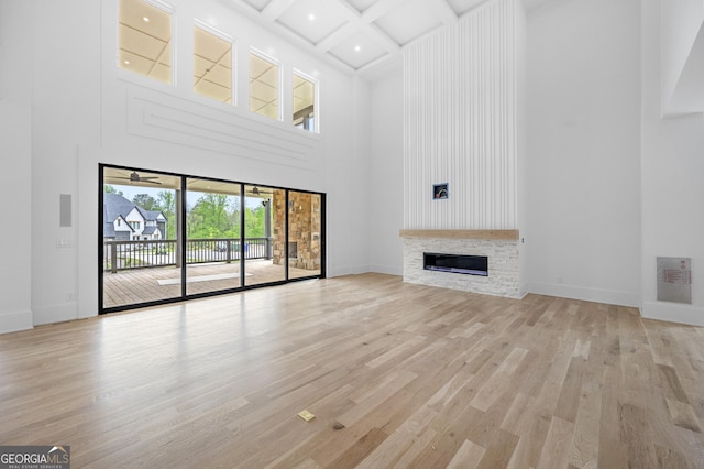 unfurnished living room featuring a towering ceiling, light hardwood / wood-style floors, and coffered ceiling