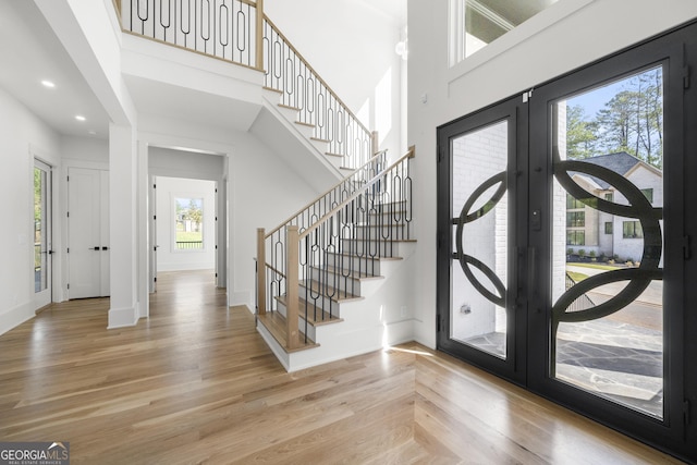 entrance foyer with hardwood / wood-style flooring, a high ceiling, and french doors