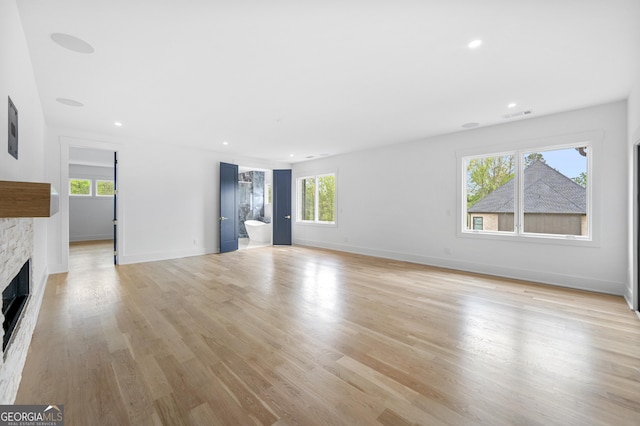 unfurnished living room featuring a wealth of natural light, a fireplace, and light hardwood / wood-style floors