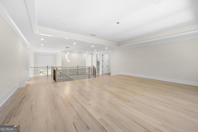 unfurnished living room featuring a tray ceiling and light wood-type flooring