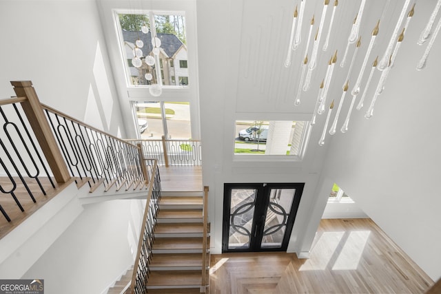 foyer entrance with french doors, a high ceiling, a healthy amount of sunlight, and wood-type flooring