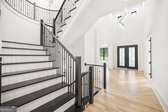 foyer featuring light parquet flooring, a high ceiling, and french doors