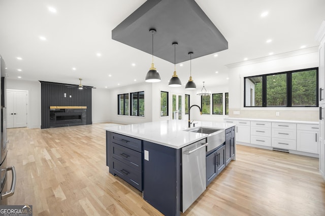 kitchen with white cabinets, a kitchen island with sink, ceiling fan, dishwasher, and hanging light fixtures