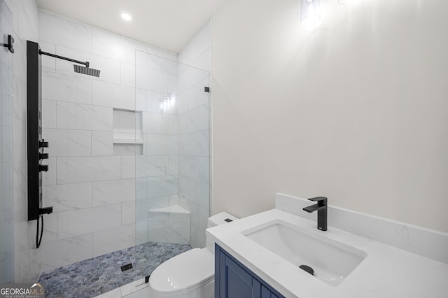 bathroom with vanity, toilet, and a tile shower