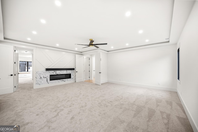 unfurnished living room with ceiling fan, light carpet, and a high end fireplace