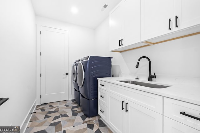 washroom with washing machine and clothes dryer, sink, dark tile patterned floors, and cabinets