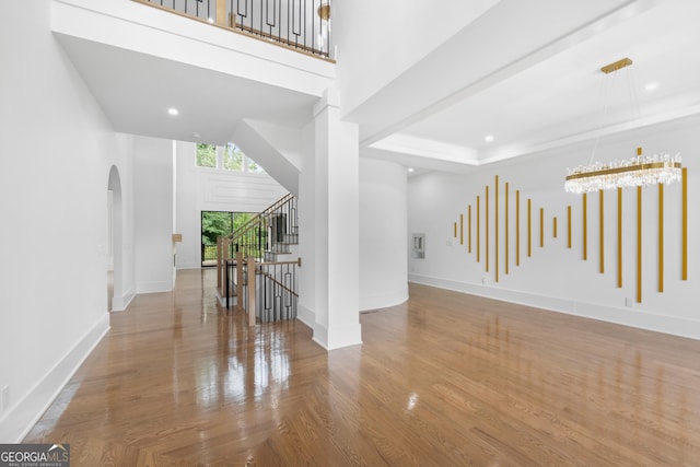 interior space featuring wood-type flooring, a high ceiling, and an inviting chandelier