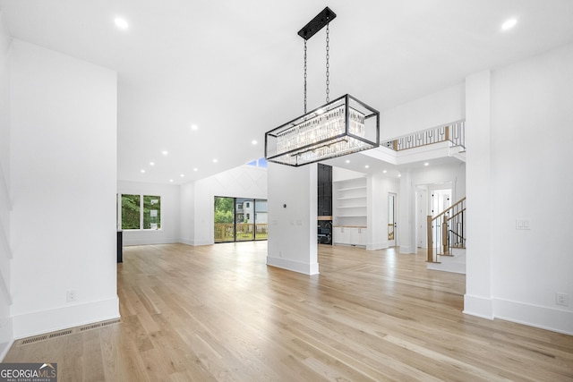 unfurnished living room with light hardwood / wood-style flooring and a high ceiling