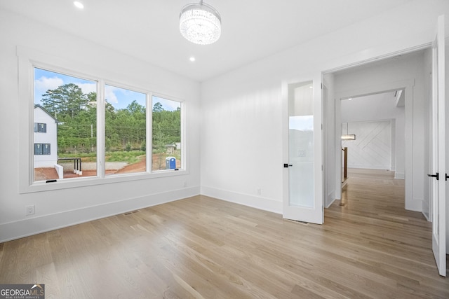 unfurnished room with light hardwood / wood-style flooring and an inviting chandelier