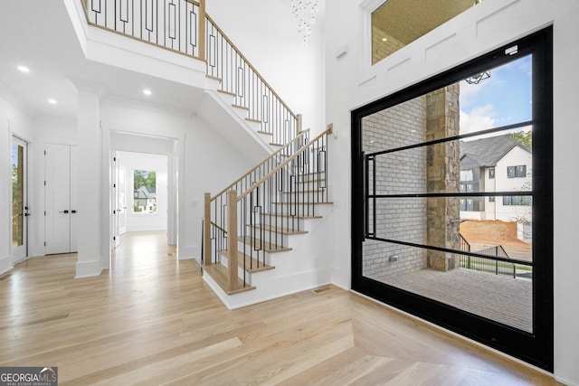 entrance foyer featuring light wood-type flooring, a high ceiling, and a wealth of natural light