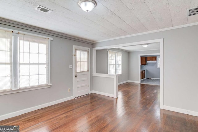 spare room featuring wood-type flooring, ornamental molding, and a brick fireplace