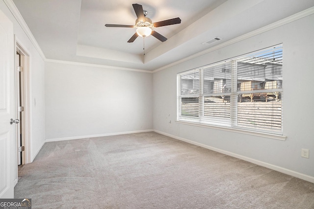 carpeted spare room featuring ceiling fan, ornamental molding, and a tray ceiling