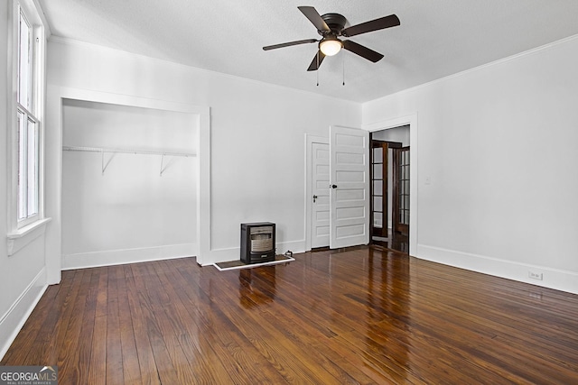 interior space with a textured ceiling, ceiling fan, dark hardwood / wood-style floors, a wood stove, and a closet