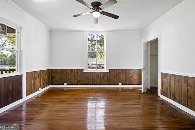 empty room featuring crown molding, ceiling fan, dark wood-type flooring, and a textured ceiling