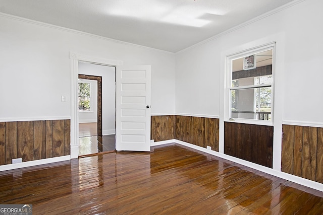 unfurnished room with wood walls, wood-type flooring, and ornamental molding