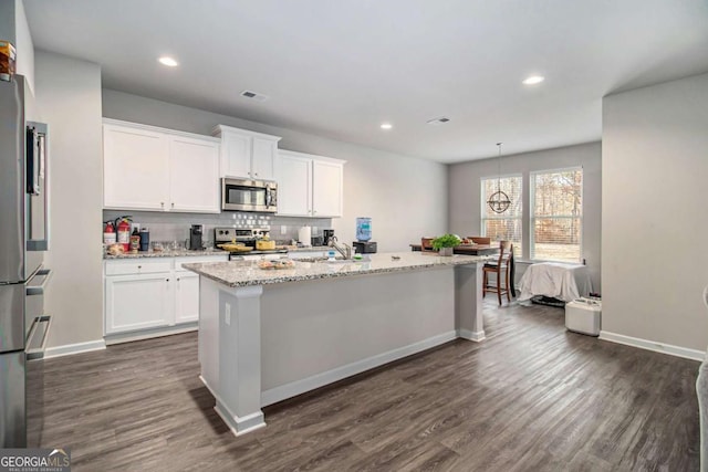 kitchen featuring a center island with sink, white cabinetry, and stainless steel appliances