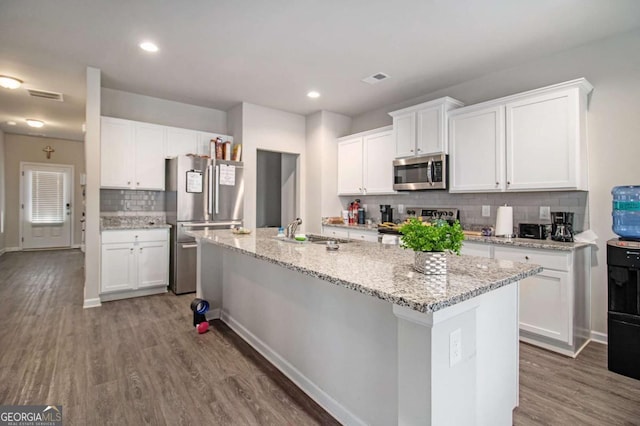 kitchen featuring stainless steel appliances, a kitchen island with sink, sink, wood-type flooring, and white cabinetry