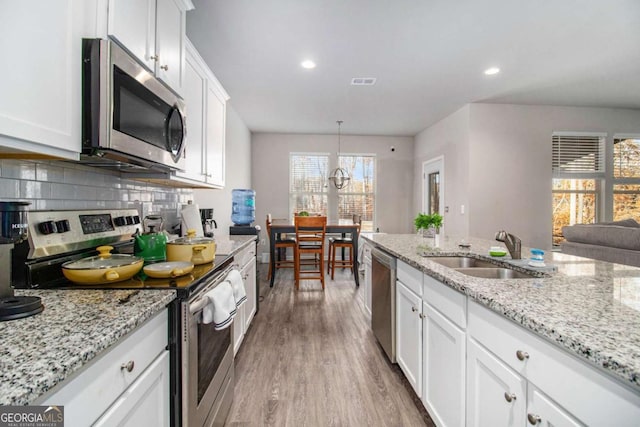 kitchen featuring white cabinetry, sink, wood-type flooring, pendant lighting, and appliances with stainless steel finishes