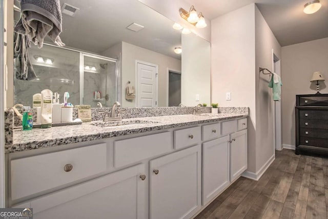 bathroom with hardwood / wood-style floors, vanity, and a shower with door