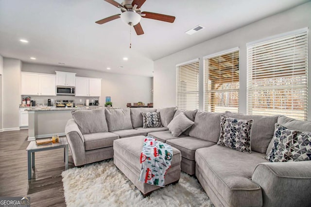 living room with ceiling fan and dark wood-type flooring