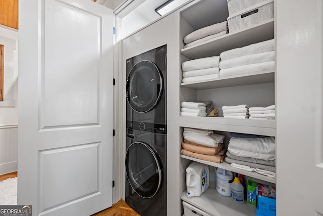 laundry room featuring stacked washer / dryer and light hardwood / wood-style flooring