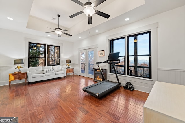 workout room with hardwood / wood-style floors, ceiling fan, french doors, and a tray ceiling